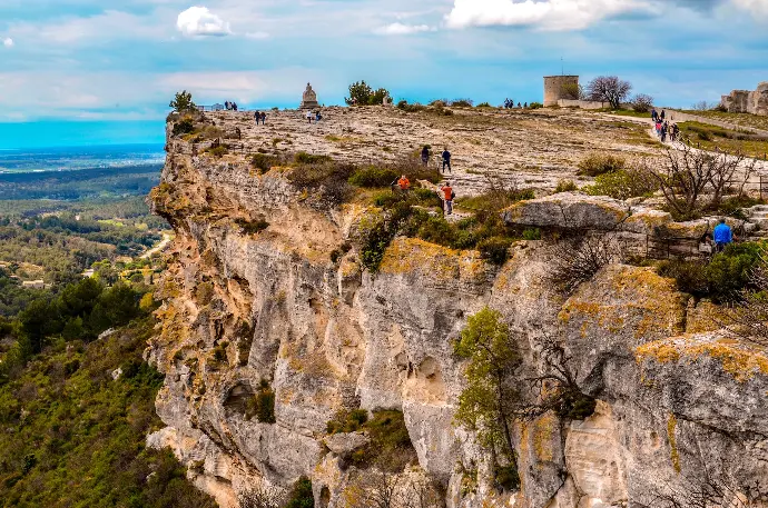 les baux de provence people climbing on brown rocky mountain under white clouds during daytime
